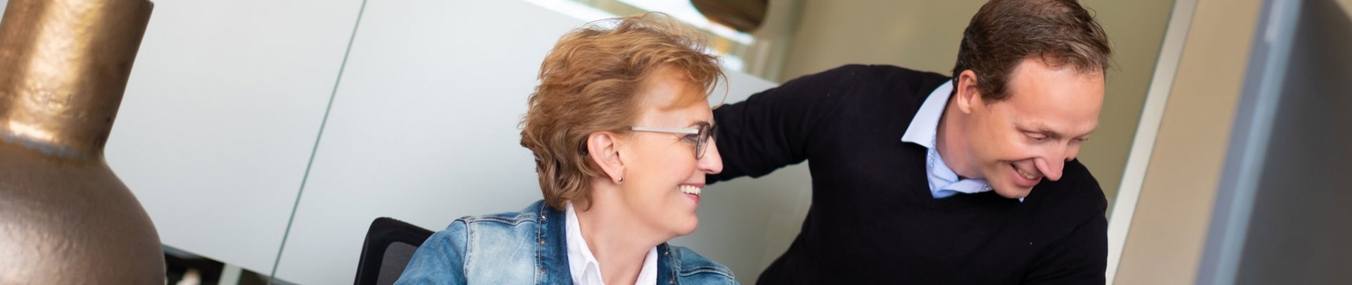 Man en vrouw zitten aan een bureau achter een computer